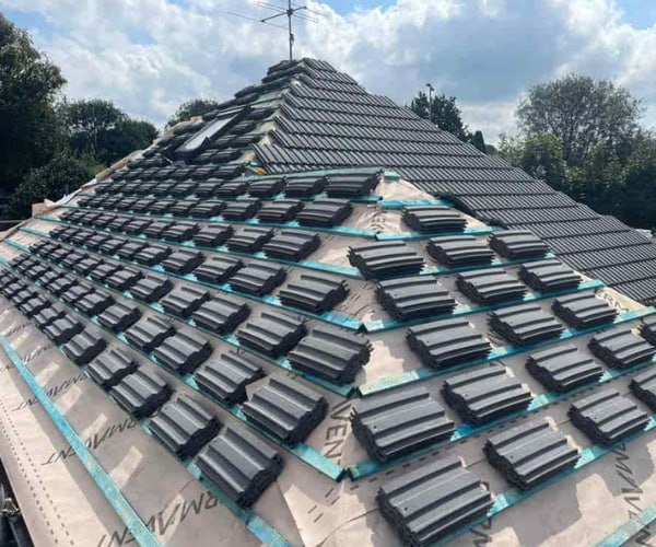 This is a photo of a new hip roof being installed. New felt, battens, and grey tiles have been installed, also a new velux window. Works carried out by KAD Roofing Bircotes.